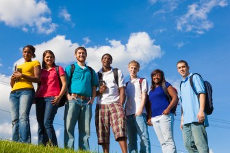 A group of diverse college students/friends outside on a hill with a sky background